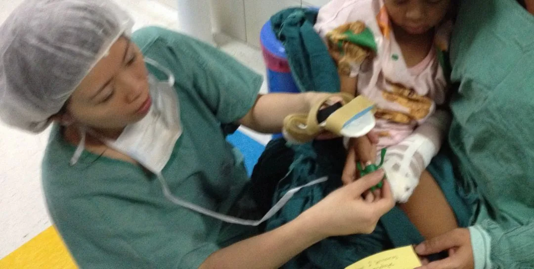 Rita fitting a custom splint on a child's arm during medical volunteering